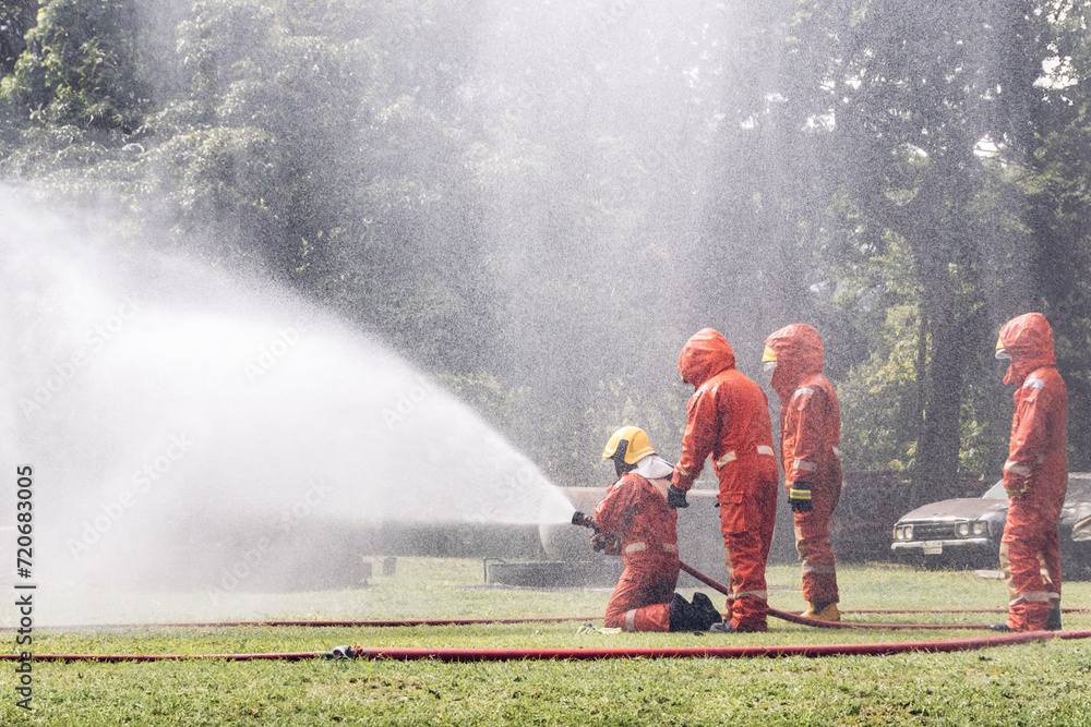 Fototapeta premium Firefighter Concept. Several firefighters go offensive for a fire attack. Fireman using water and extinguisher to fighting with fire flame.