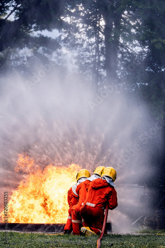 Firefighter Concept. Several firefighters go offensive for a fire attack. Fireman using water and extinguisher to fighting with fire flame.