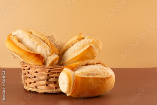 Fresh baked flour bread inside a basket in beige and brown background in front view angle with empty blank space