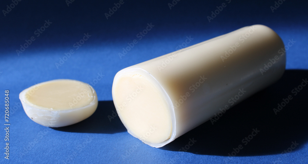String italian cheese in a paraffin coating isolated on blue background, close up. String italian cheese in a paraffin coating isolated on blue background, close up.