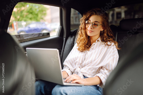 Young woman uses laptop in car. Remote work. Business, blogging, freelance, Online shopping, education concept. © maxbelchenko