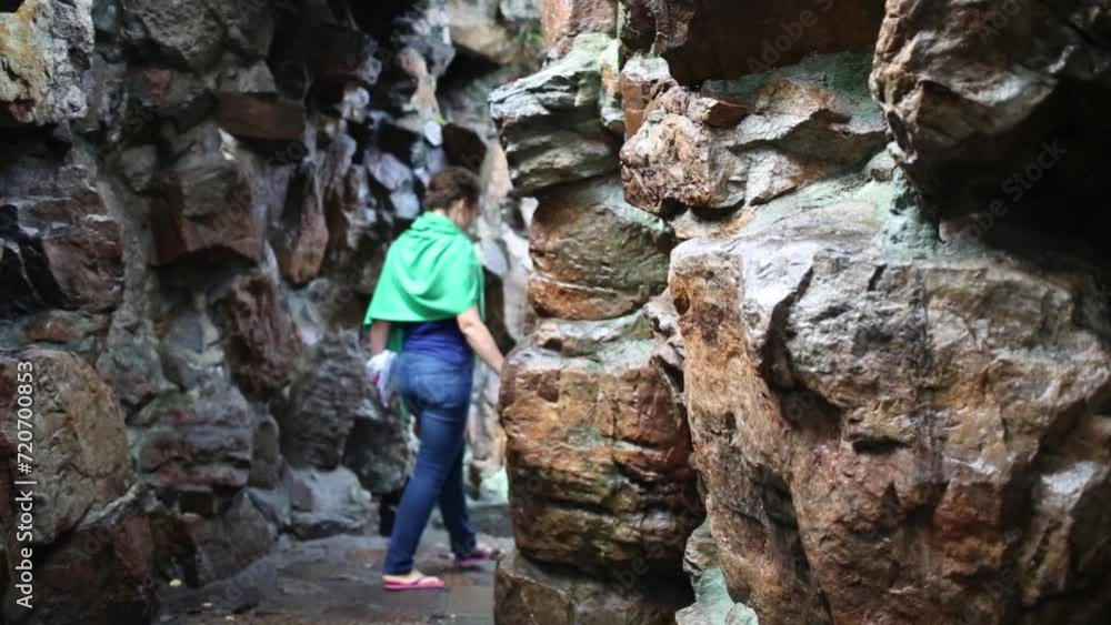 Woman in jeans goes among big rocks on path, back view Woman in jeans goes among big rocks on path, back view