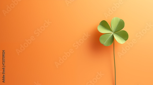 Imagen minimalista de un trébol de cuatro hojas sobre un fondo de color naranja claro con espacio para meter texto photo