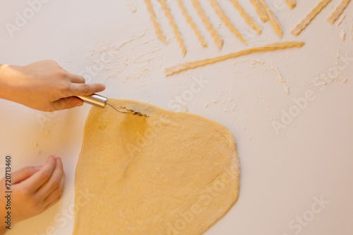 Child making homemade pasta at kitchen