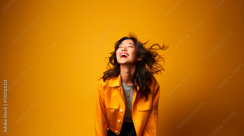 Portrait of a beautiful young asian woman laughing on yellow background Portrait of a beautiful young asian woman laughing on yellow background