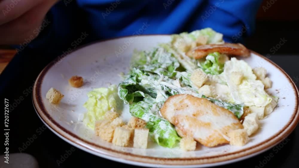 Hand with chopsticks taking leaf of salad Caesar form plate close-up. Hand with chopsticks taking leaf of salad Caesar form plate close-up.
