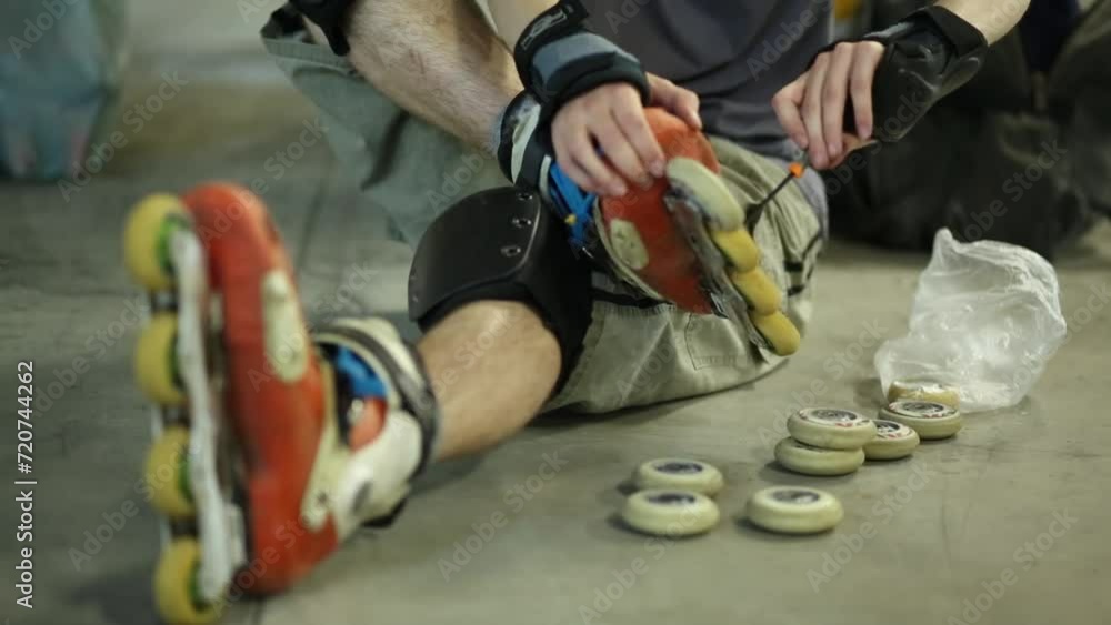 Guy on roller skates sitting and screwing wheel to skate. Guy on roller skates sitting and screwing wheel to skate.