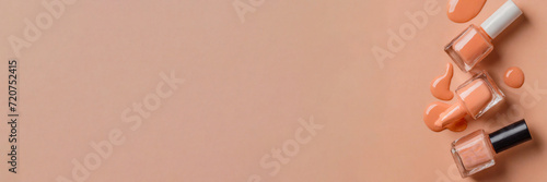 Panorama. Nail polish bottle in peach tone spilled on soft peach fuzz color background. Panoramic view with a large copy space for text. photo