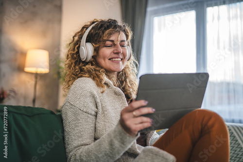 Woman sit at home use digital tablet to watch movie or have video call photo