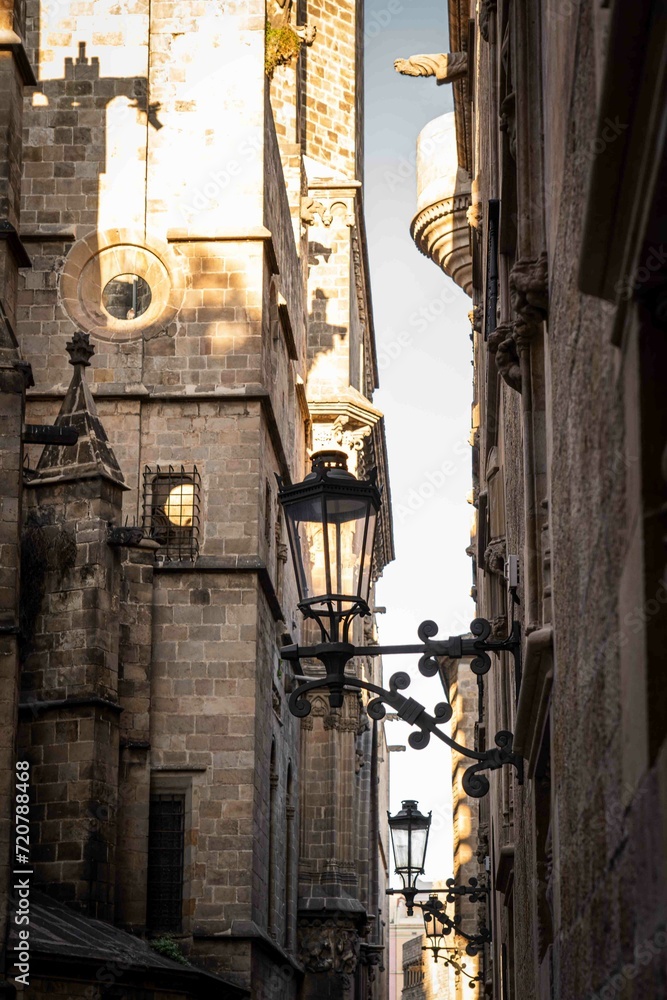 calle de la zona antigua de una ciudad europea, Barcelona, donde se ve una farola y una iglesia