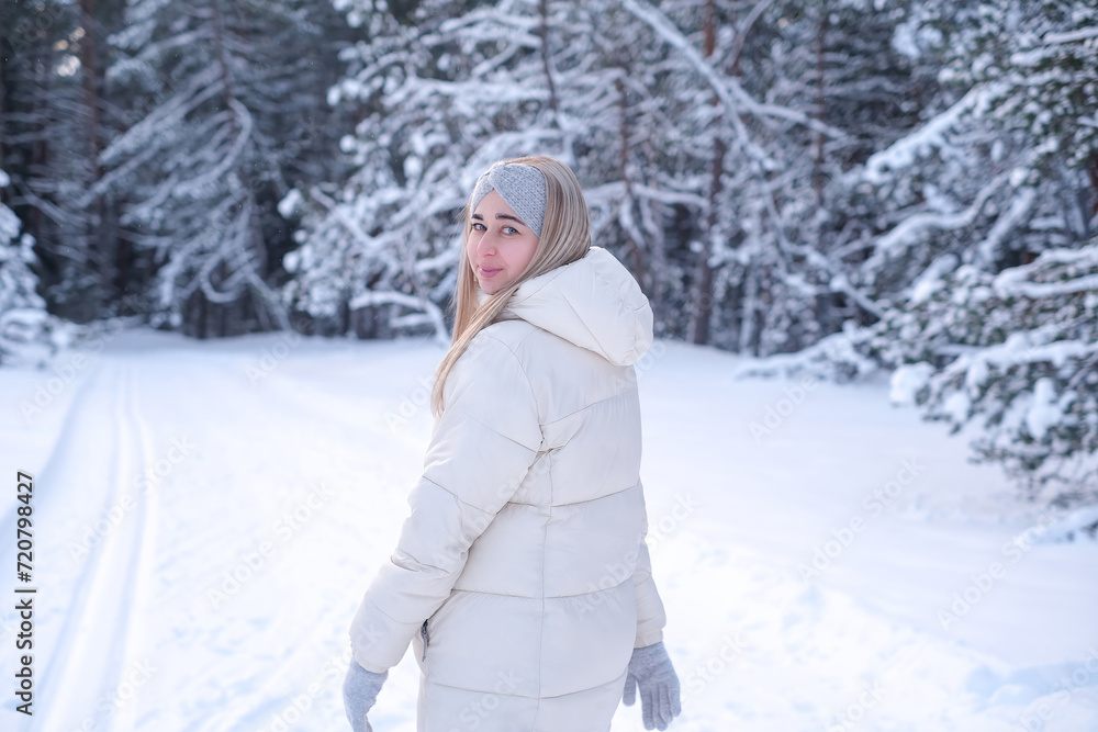 A woman in a white jacket and hat standing in the snow A woman in a white jacket and hat standing in the snow