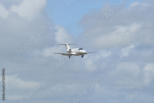 Small jet airplane flying in the sky with clouds, approach to the landing strip maneuver