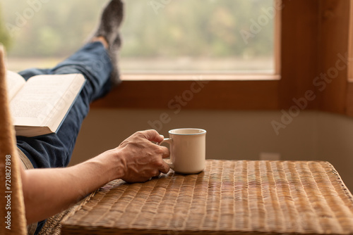 Photographie Person at home relaxing with feet up by the window reading and enjoying a mornin
