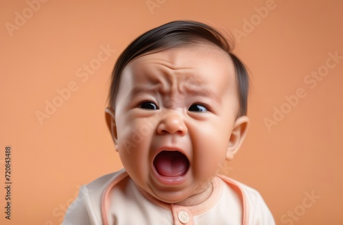 closeup of Asian boy toddler crying loudly on beige background, attentive baby care