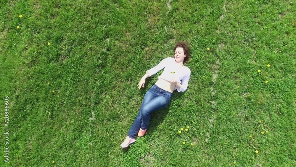 Woman lies on grassplot near road with transport traffic Woman lies on grassplot near road with transport traffic
