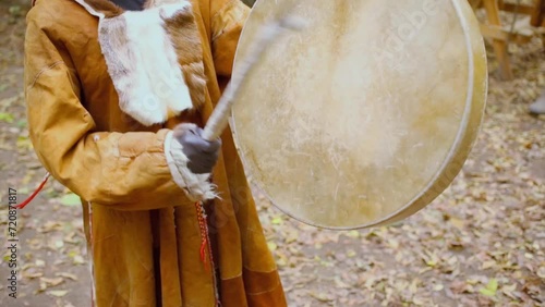 Woman in native fur clothes beats tambourine at autumn day photo