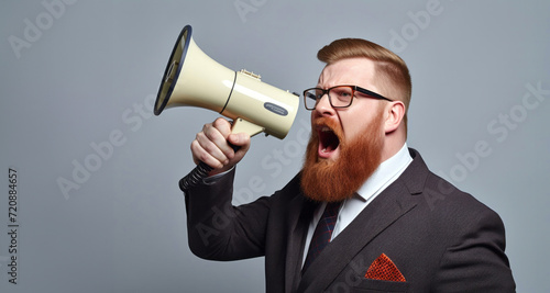 Portrait of a red-bearded businessman shouting through a megaphone © YannTouvay