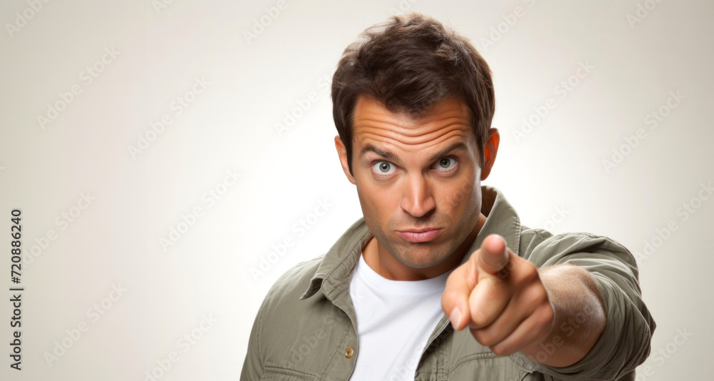 young casual man pointing to the front with a serious expression on grey background young casual man pointing to the front with a serious expression on grey background