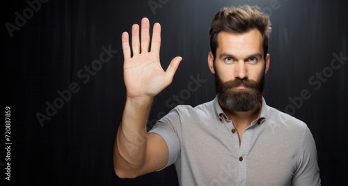 Man with beard and mustache making stop gesture with his hand on black background photo