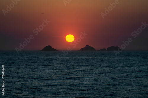 Red sunset dusk sky view saw from Arpoador rock (Pedra do Arpoador) with Tijucas islands in sight on the horizon under summer afternoon sunny clear sky in Ipanema district in Rio de Janeiro - Brazil. photo