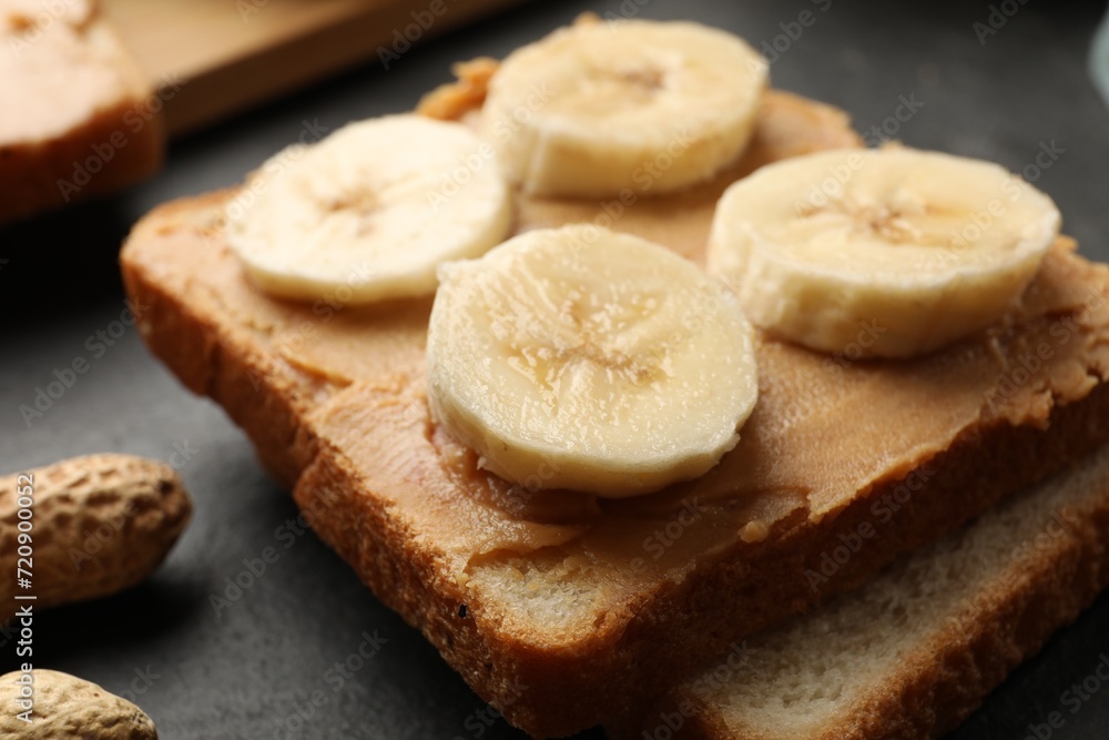 Tasty peanut butter sandwich and sliced banana on table, closeup