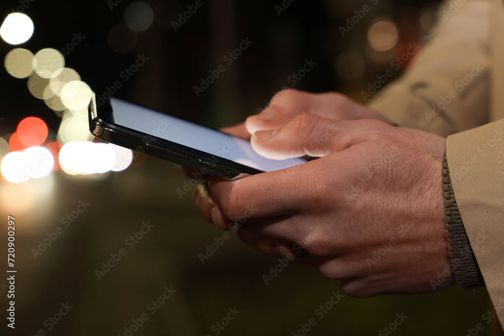 Man using smartphone on night city street, closeup