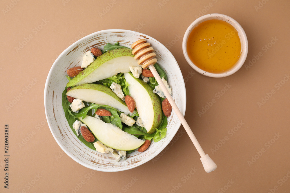 Delicious pear salad in bowl, honey and dipper on beige background, top view Delicious pear salad in bowl, honey and dipper on beige background, top view