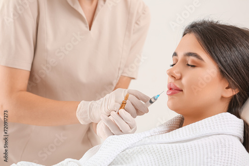 Young woman receiving lip injection in beauty salon, closeup