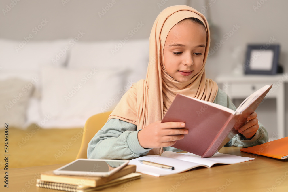 Little Muslim girl in hijab doing homework at home Little Muslim girl in hijab doing homework at home
