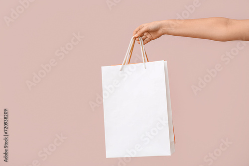 Female hand with paper shopping bags on light background. Valentine's Day celebration