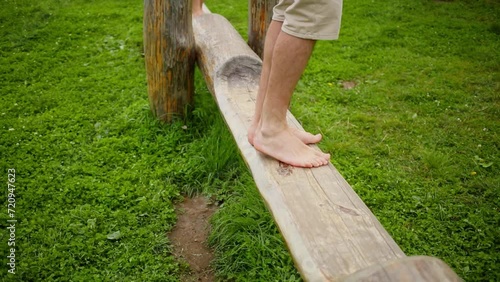 Man teeters on swing with young girl at summer day
