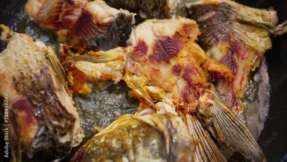 Several pieces of fish is being fried in hot oil at pan Several pieces of fish is being fried in hot oil at pan