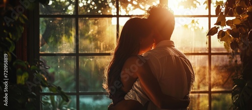People embracing by a window, experiencing peace, romance, support, relaxation, commitment, loyalty, trust, and unity in a relationship or marriage.