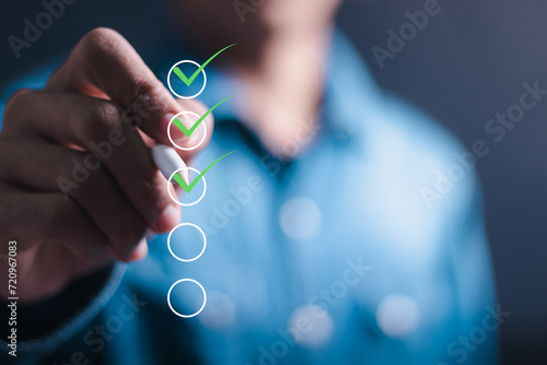 Businessman using pen checking mark on checkboxes for checklist concept.