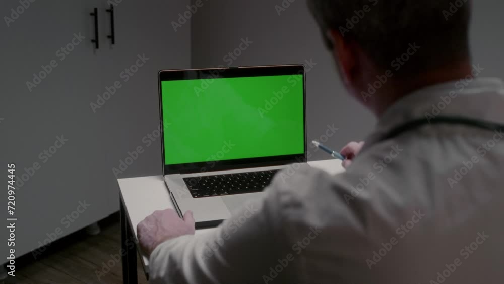 Professional male doctor in work uniform looks at laptop screen listening to patient and pointing with pen to image area. Chromakey for inserting photo and video concept slow motion Professional male doctor in work uniform looks at laptop screen listening to patient and pointing with pen to image area. Chromakey for inserting photo and video concept slow motion