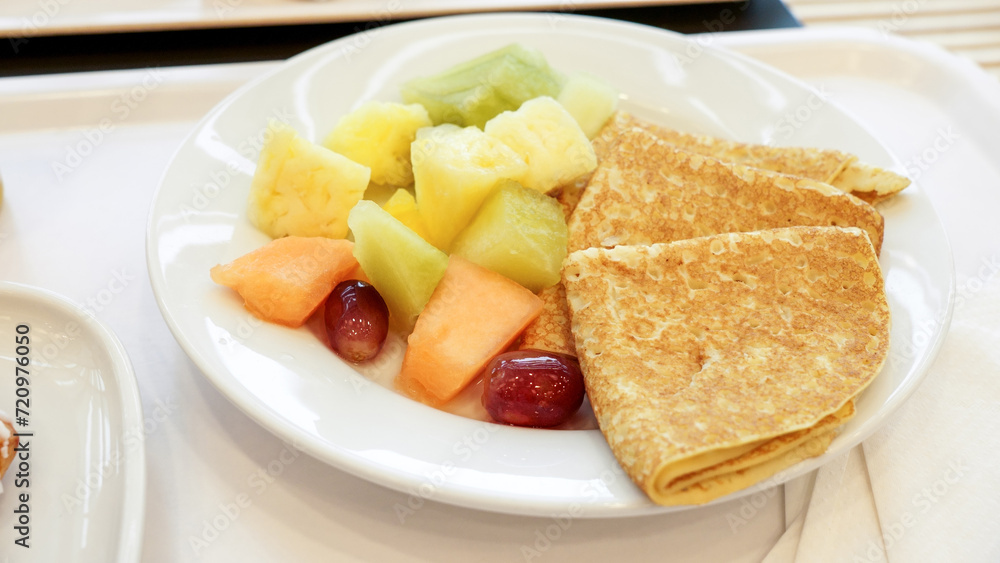 Delicious fresh fruits and freshly baked pancakes on white plate. Breakfast at restaurant. Delicious fresh fruits and freshly baked pancakes on white plate. Breakfast at restaurant.