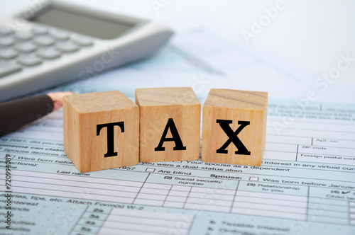 Tax wordings on wooden cubes with tax form and calculator background. Taxation concept