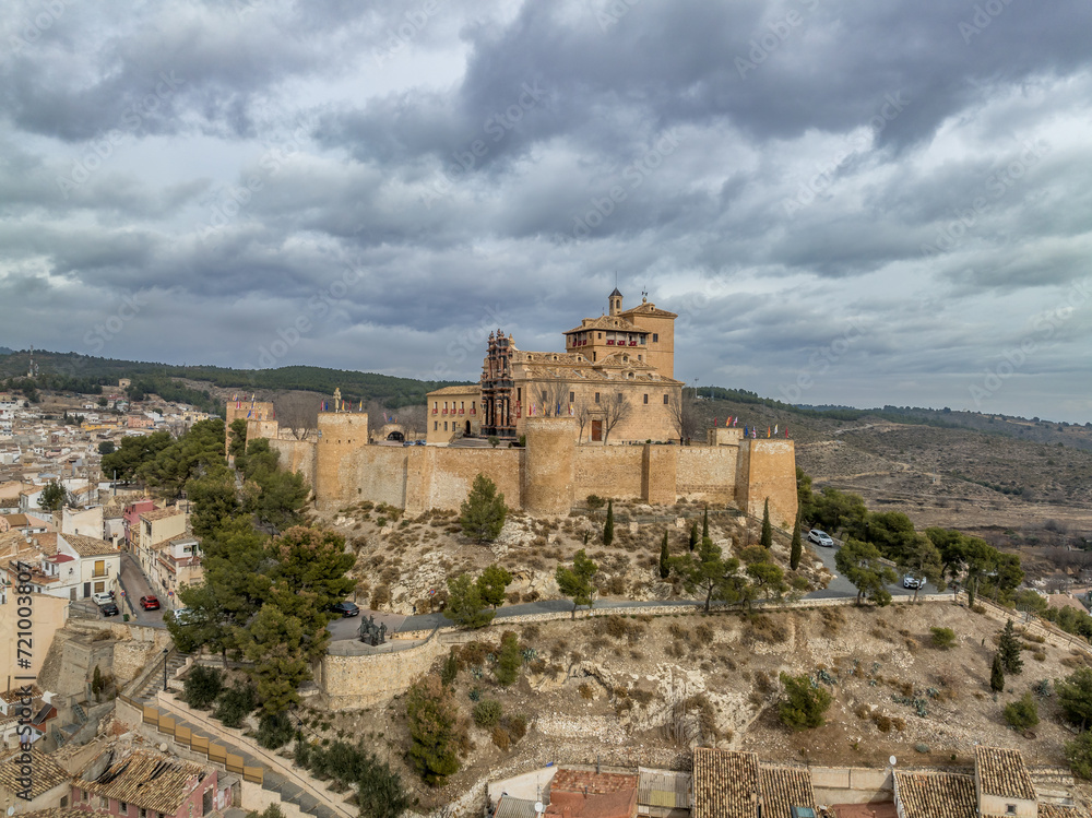 Aerial view of Caravaca de la Cruz castle dominating the landscape with square and circular towers, medieval palace and Baroque ornament facade church