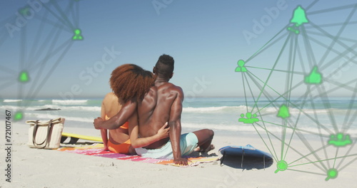 Image of spinning networks with social media digital icons over couple embracing on beach