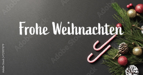 Frohe weihnachten text with candy canes, christmas tree branch and baubles on grey background