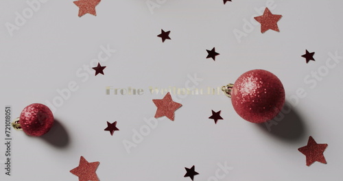 Red Christmas ornaments lie among scattered stars on a surface