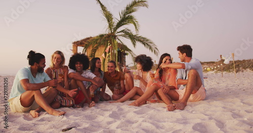 Diverse group of friends enjoy a beach sunset, with copy space