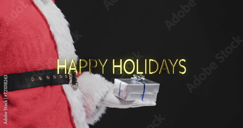 Happy holidays text in gold over father christmas holding present on black background