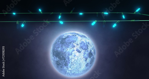 Blue christmas string lights flashing over falling snow and full moon in night sky