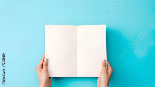 hands holding Mock up of a book, plain space, empty cover on bright blue backdrop 