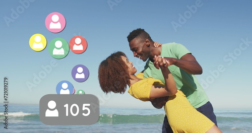 Profile icons with increasing numbers against african american couple dancing on the beach