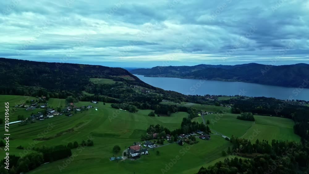 Village in green fields on shore of mountain lake below cloudy sky. Village in green fields on shore of mountain lake below cloudy sky.