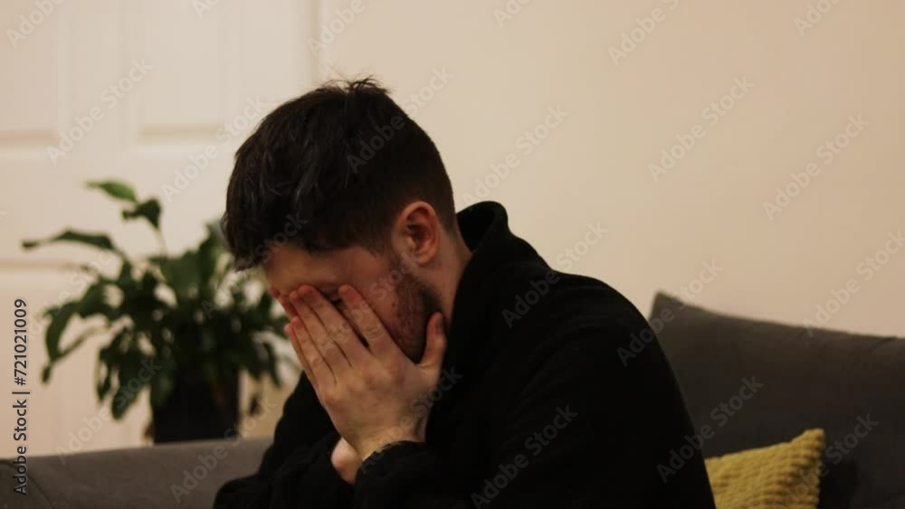 Young man with his head in hands with regret or despair sitting on couch in home. Static. Young man with his head in hands with regret or despair sitting on couch in home. Static.