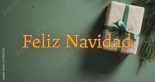 Feliz navidad text in orange over christmas gift on green background