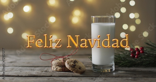 Feliz navidad text in orange over christmas cookies and milk and bokeh lights background